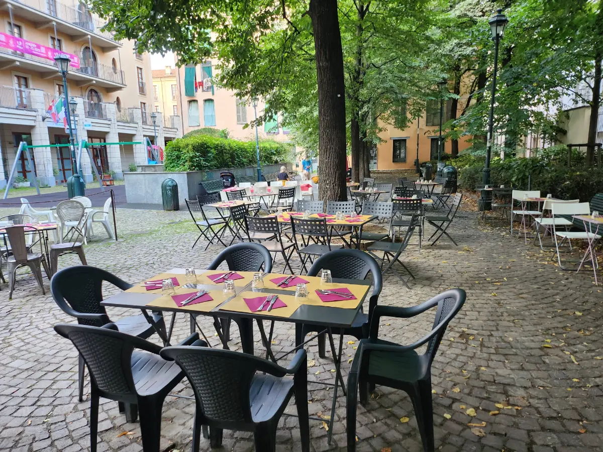 Il dehors: tavoli apparecchiati sul pavé, sotto gli alberi